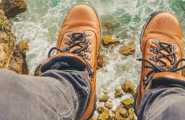 Lederschuhe von oben vor Klippen und Meer